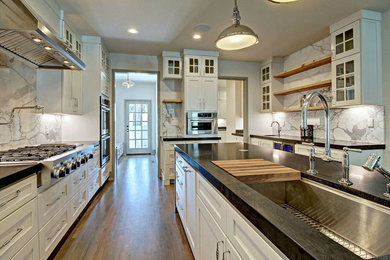 Foto på ett avskilt, stort vintage l-kök, med en undermonterad diskho, luckor med profilerade fronter, vita skåp, granitbänkskiva, vitt stänkskydd, stänkskydd i sten, rostfria vitvaror, mellanmörkt trägolv och en köksö