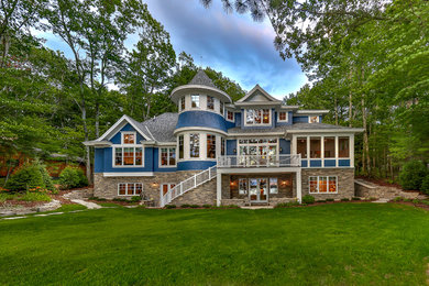 Large elegant blue two-story wood house exterior photo in Other with a shingle roof