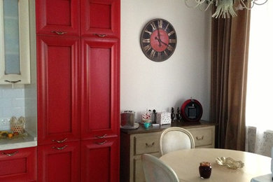 На фото: угловая кухня среднего размера в классическом стиле с обеденным столом, фасадами с выступающей филенкой, красными фасадами, столешницей из акрилового камня, белым фартуком, полом из керамогранита и бежевым полом