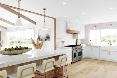 Large l-shaped light wood floor eat-in kitchen photo in Boston with a farmhouse sink, raised-panel cabinets, white cabinets, white backsplash, subway tile backsplash, stainless steel appliances, an island and white countertops