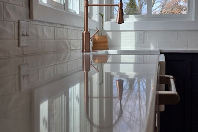 Inspiration for a large transitional vinyl floor and brown floor eat-in kitchen remodel in Columbus with a farmhouse sink, shaker cabinets, blue cabinets, quartz countertops, white backsplash, porcelain backsplash, white appliances, an island and white countertops