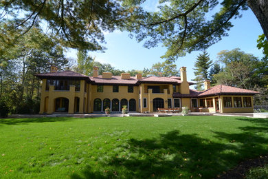 Example of a huge tuscan yellow two-story stucco house exterior design in Chicago with a hip roof and a tile roof