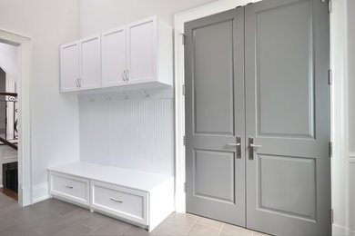Example of a mid-sized transitional porcelain tile and gray floor mudroom design in Orange County with white walls