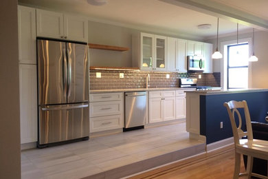 This is an example of a mid-sized traditional galley kitchen pantry in New York with a single-bowl sink, white cabinets, quartzite benchtops, grey splashback, subway tile splashback, stainless steel appliances, a peninsula, beige floor, vinyl floors, multi-coloured benchtop, vaulted and recessed-panel cabinets.