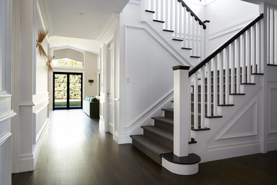 Photo of a large traditional wood u-shaped staircase in Sydney with painted wood risers and wood railing.
