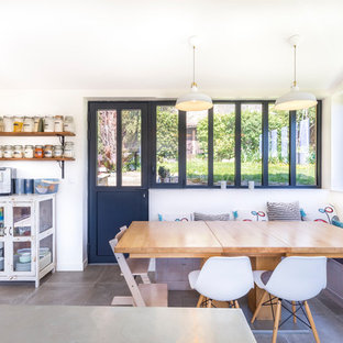 Cette image montre une salle à manger ouverte sur la cuisine design avec un mur blanc et un sol gris.