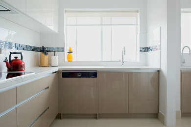 Imagen de cocina comedor minimalista sin isla con armarios estilo shaker, puertas de armario de madera clara, encimera de cuarzo compacto y salpicadero blanco