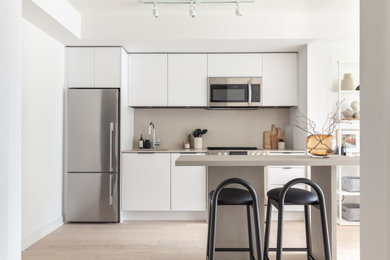 Eat-in kitchen - small scandinavian single-wall light wood floor and beige floor eat-in kitchen idea in Toronto with an undermount sink, flat-panel cabinets, white cabinets, quartz countertops, gray backsplash, quartz backsplash, stainless steel appliances, an island and gray countertops