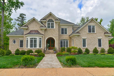 Beige three-story brick gable roof photo in Other