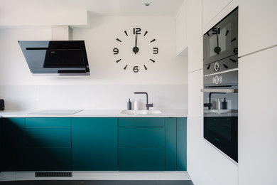 This is an example of a mid-sized modern u-shaped separate kitchen in Other with an undermount sink, flat-panel cabinets, green cabinets, quartz benchtops, white splashback, stone slab splashback, black appliances, vinyl floors, no island, black floor and white benchtop.