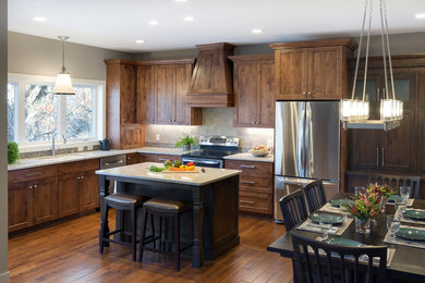 Photo of a mid-sized transitional l-shaped open plan kitchen in Minneapolis with an undermount sink, shaker cabinets, dark wood cabinets, granite benchtops, multi-coloured splashback, subway tile splashback, stainless steel appliances, vinyl floors, with island and brown floor.