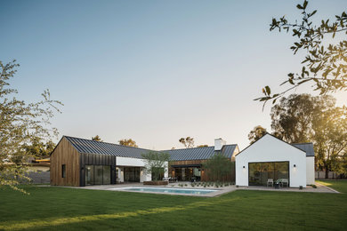 Ejemplo de fachada de casa blanca y negra escandinava grande de una planta con revestimiento de madera, tejado a dos aguas y tejado de metal