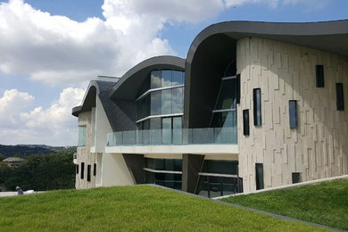 Huge contemporary beige three-story stone exterior home idea in Austin with a metal roof