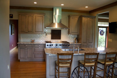 Inspiration for a mid-sized transitional galley medium tone wood floor eat-in kitchen remodel in Other with a farmhouse sink, recessed-panel cabinets, gray cabinets, granite countertops, white backsplash, ceramic backsplash, stainless steel appliances and a peninsula