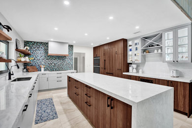 Example of a minimalist eat-in kitchen design with flat-panel cabinets, medium tone wood cabinets, blue backsplash, an island and white countertops