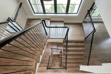 ワシントンD.C.にある高級な巨大なエクレクティックスタイルのおしゃれな折り返し階段 (木の蹴込み板、混合材の手すり) の写真
