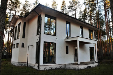 На фото: двухэтажный, белый частный загородный дом среднего размера в скандинавском стиле с облицовкой из цементной штукатурки