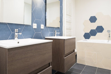 他の地域にある高級な中くらいなコンテンポラリースタイルのおしゃれなマスターバスルーム (バリアフリー、壁掛け式トイレ、ベージュのタイル、セラミックタイル、青い壁、磁器タイルの床、コンソール型シンク、グレーの床、開き戸のシャワー、トイレ室、洗面台2つ) の写真