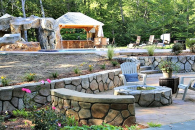 Patio kitchen - mid-sized rustic backyard stone patio kitchen idea in Boston with a pergola