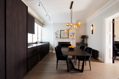 Design ideas for a mid-sized contemporary single-wall eat-in kitchen in London with an integrated sink, dark wood cabinets, granite benchtops, black splashback, stainless steel appliances, no island, brown floor, black benchtop, flat-panel cabinets and medium hardwood floors.