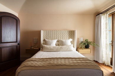 Example of a mid-sized beach style guest medium tone wood floor and vaulted ceiling bedroom design in San Diego with pink walls