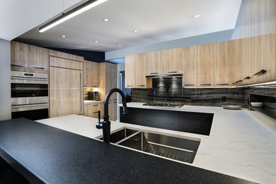 Design ideas for a large modern u-shaped eat-in kitchen in Toronto with flat-panel cabinets, light wood cabinets, quartz benchtops, black splashback, porcelain splashback, a peninsula and white benchtop.