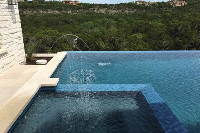 Inspiration for a large modern backyard concrete and rectangular infinity hot tub remodel in Austin