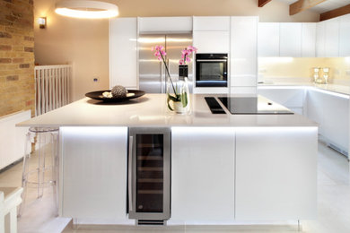 Photo of a large contemporary u-shaped open plan kitchen in Oxfordshire with flat-panel cabinets, white cabinets, quartz worktops, stainless steel appliances, an island, white worktops, limestone flooring, white floors, exposed beams and feature lighting.