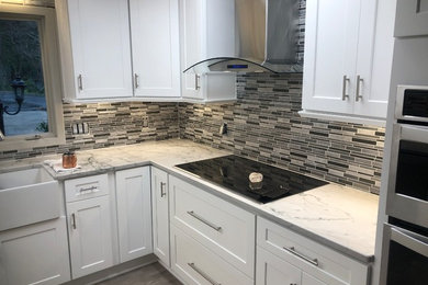 Example of a mid-sized trendy u-shaped light wood floor and gray floor eat-in kitchen design in Atlanta with a farmhouse sink, shaker cabinets, white cabinets, quartzite countertops, gray backsplash, mosaic tile backsplash, stainless steel appliances, no island and white countertops