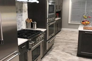 Example of a large transitional u-shaped porcelain tile and gray floor eat-in kitchen design in Detroit with a farmhouse sink, shaker cabinets, dark wood cabinets, quartz countertops, gray backsplash, marble backsplash, stainless steel appliances and a peninsula