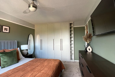 Diseño de dormitorio principal actual de tamaño medio sin chimenea con paredes verdes y moqueta