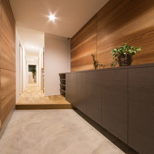 他の地域の引き戸モダンスタイルのおしゃれな玄関 (茶色い壁、コンクリートの床、グレーの床) の写真