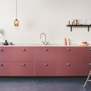 Idee per una piccola cucina design con lavello da incasso, ante lisce, ante rosse, top in superficie solida, paraspruzzi beige, paraspruzzi in lastra di pietra, elettrodomestici da incasso, pavimento in legno verniciato, nessuna isola, pavimento nero e top beige