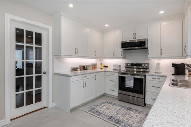Minimalist porcelain tile and gray floor kitchen photo in Toronto with a double-bowl sink, white backsplash, porcelain backsplash, stainless steel appliances, no island, shaker cabinets, white cabinets and laminate countertops