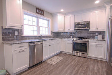 Mid-sized minimalist l-shaped kitchen photo in New York with shaker cabinets, white cabinets, gray backsplash, subway tile backsplash, stainless steel appliances and no island