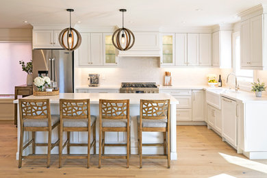 Large trendy l-shaped light wood floor and beige floor eat-in kitchen photo in Toronto with shaker cabinets, white cabinets, white backsplash, an island, white countertops, granite countertops, ceramic backsplash, stainless steel appliances and a farmhouse sink