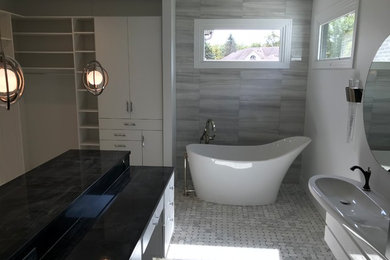 Freestanding bathtub - mid-sized contemporary master gray tile and porcelain tile marble floor and white floor freestanding bathtub idea in Other with flat-panel cabinets, white cabinets, white walls, an integrated sink, solid surface countertops and white countertops