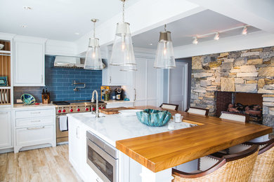 This is an example of a large transitional u-shaped eat-in kitchen in Milwaukee with recessed-panel cabinets, white cabinets, marble benchtops, blue splashback, ceramic splashback, white appliances, light hardwood floors, multiple islands and beige floor.