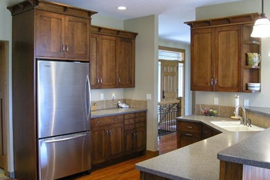 Inspiration for a mid-sized transitional l-shaped medium tone wood floor enclosed kitchen remodel in Cedar Rapids with a double-bowl sink, medium tone wood cabinets, beige backsplash and stainless steel appliances