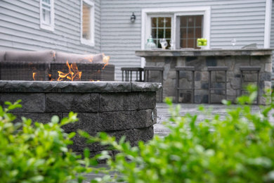This is an example of a mid-sized modern backyard stone landscaping in Other with a fire pit.