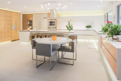 Inspiration for a large modern l-shaped ceramic tile open concept kitchen remodel in Calgary with a double-bowl sink, flat-panel cabinets, white cabinets, solid surface countertops, white backsplash, stone slab backsplash, paneled appliances and an island