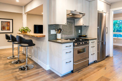 This is an example of a contemporary kitchen in San Francisco with flat-panel cabinets, grey cabinets, quartz benchtops, grey splashback, glass tile splashback, stainless steel appliances and medium hardwood floors.