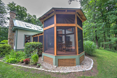This is an example of a mid-sized brick screened-in back porch design in Other with a roof extension.