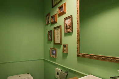 Mid-sized transitional powder room in Yokohama with green walls, a vessel sink, wood benchtops, recessed-panel cabinets, light wood cabinets, brown benchtops, a one-piece toilet, laminate floors and brown floor.