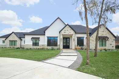 Large transitional white one-story stucco house exterior photo in Houston with a hip roof, a shingle roof and a black roof