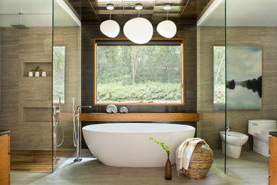 Photo of an asian master bathroom in Atlanta with medium wood cabinets, a freestanding tub, a corner shower, a one-piece toilet and beige tile.