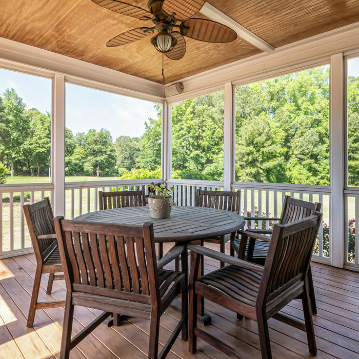 Covered outdoor patio with ceiling fan and seating on a bright summers day