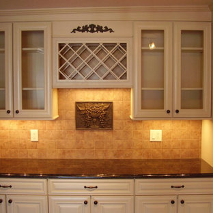 フィラデルフィアの中サイズのトラディショナルスタイルのおしゃれなウェットバー (シンクなし、レイズドパネル扉のキャビネット、白いキャビネット、御影石カウンター、茶色いキッチンパネル、トラバーチンの床、黒いキッチンカウンター) の写真