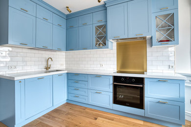 Идея дизайна: отдельная, угловая кухня среднего размера в стиле неоклассика (современная классика) с синими фасадами, столешницей из кварцевого агломерата, белой столешницей и красивой плиткой