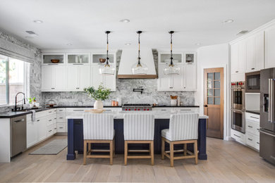 Inspiration for a mid-sized transitional u-shaped light wood floor open concept kitchen remodel in Orange County with an undermount sink, shaker cabinets, white cabinets, marble countertops, white backsplash, marble backsplash, stainless steel appliances, an island and white countertops